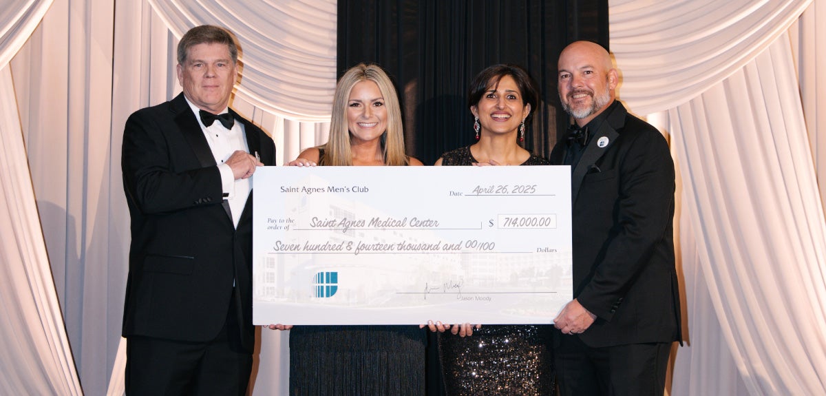Group standing with large check